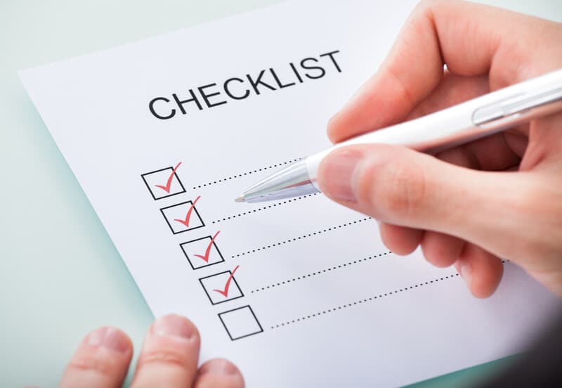 Close-up of a person's hand marking on checklist with pen