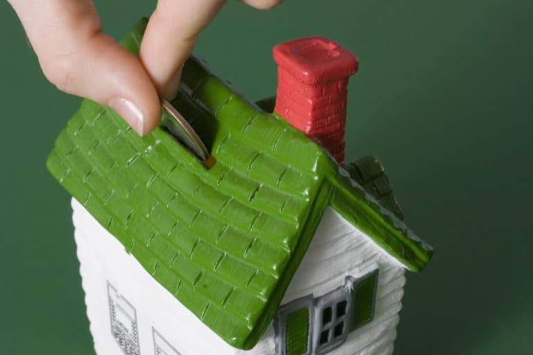 Person putting money in a bank shaped like a house