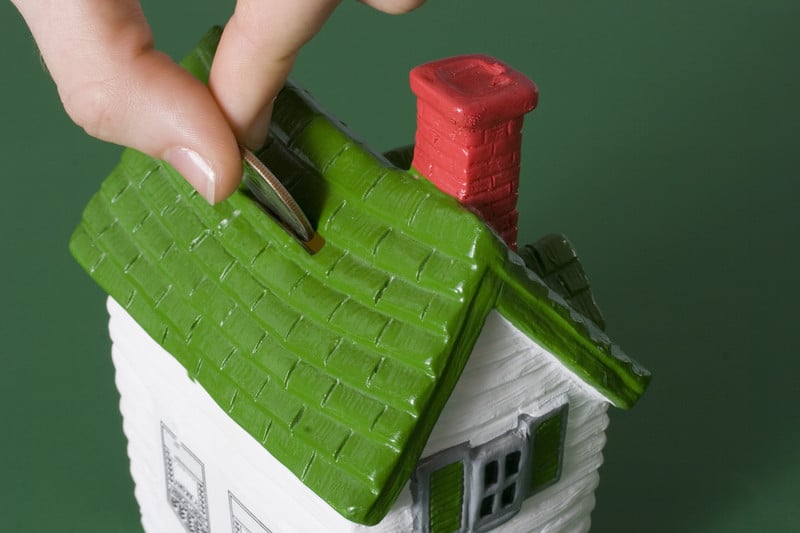 Person putting money in a bank shaped like a house